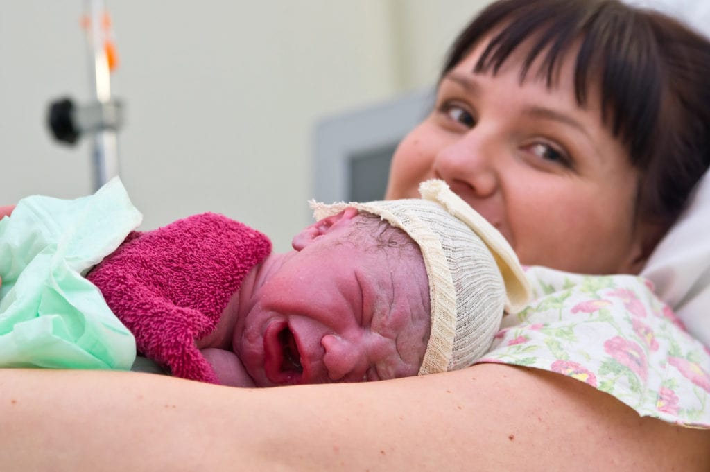 Young woman with newborn baby in maternity hospital