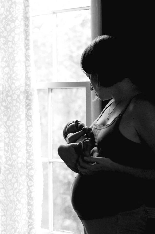 postpartum woman holding newborn by woman