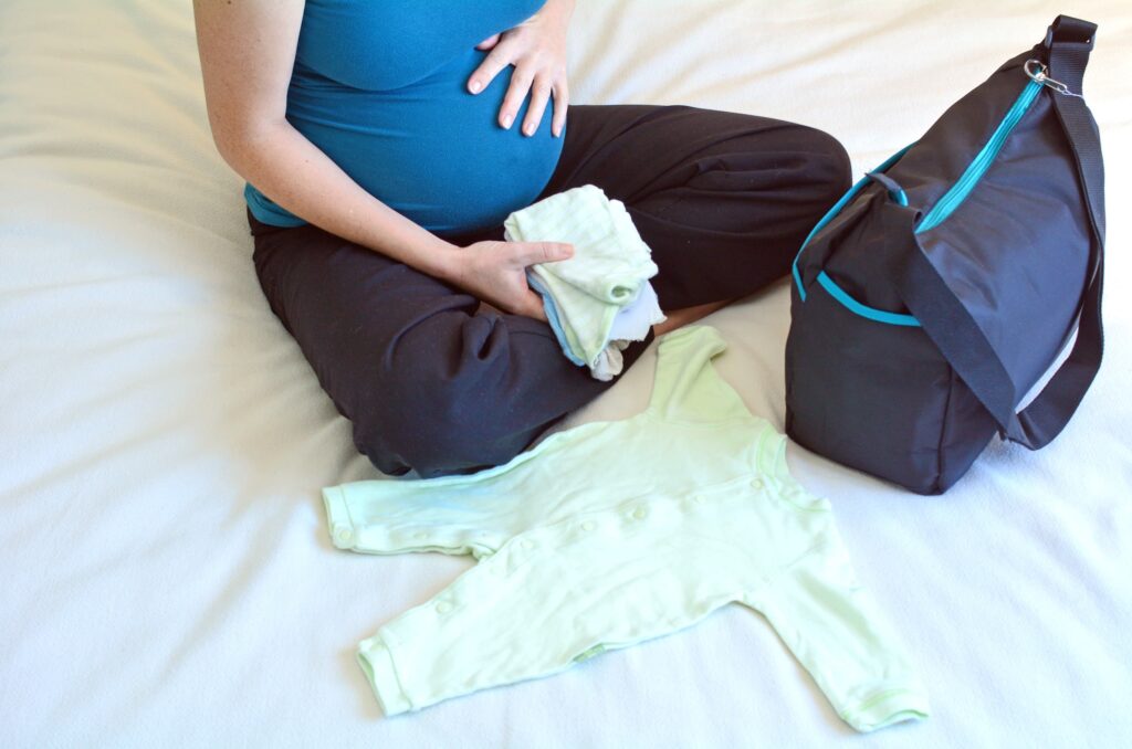 Pregnancy - pregnant woman packing a Hospital Bag. Concept photo of pregnant women life style and health care. copy space