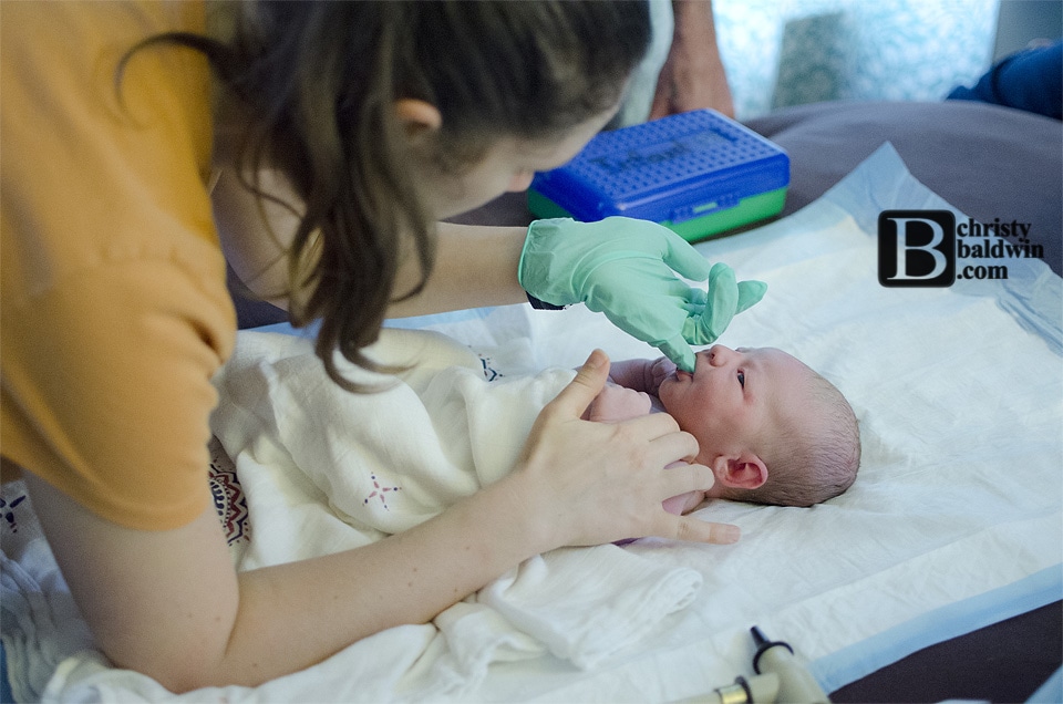 Midwifery student checking the palate of a newborn during the newborn exam after homebirth. 