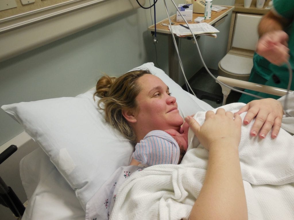 mom in recovery after a gentle c section with skin to skin with newborn