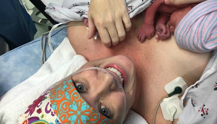 woman in operating room immediately following a cesarean birth with baby on chest