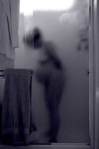 pregnant woman in labor standing in shower behind shower door