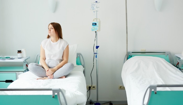 alone woman sitting on white hospital bed