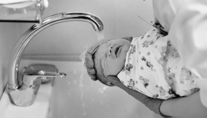 newborn baby being bathed
