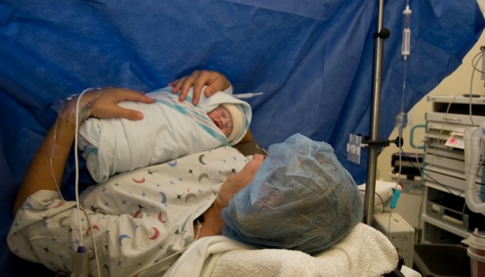 newborn baby swaddled being held by mother having a cesarean birth