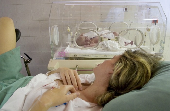 Mother watches baby in isolate during third stage of labor.