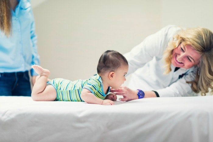 doctor looking at baby on exam table with other woman in background