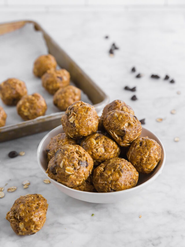 Lactation energy bites in a white bowl in front of the same in lines on a baking sheet.