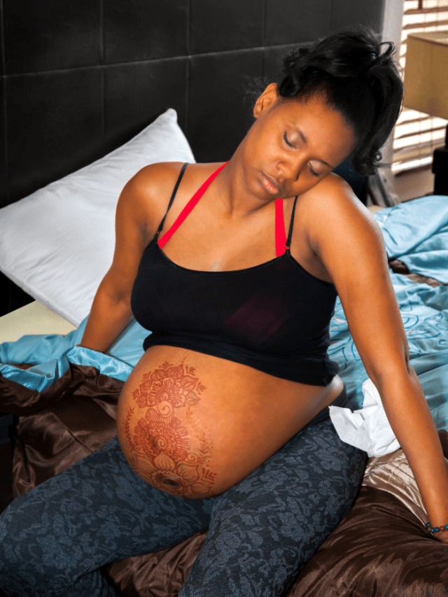African American woman in labor on bed with henna on belly