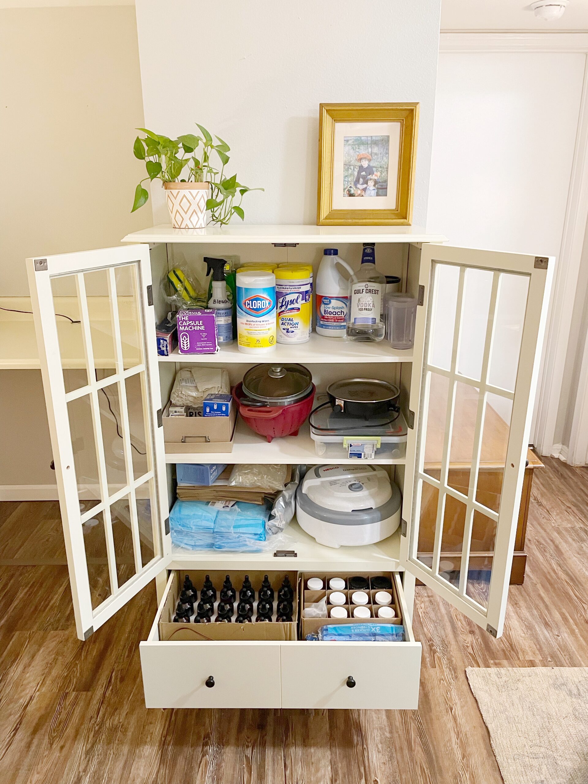 white cabinet with two shelves and bottom drawer full of placenta encapsulation supplies