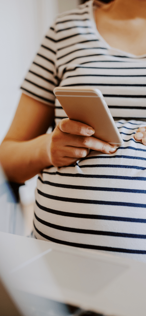 pregnant woman in striped shirt on phone and touching belly