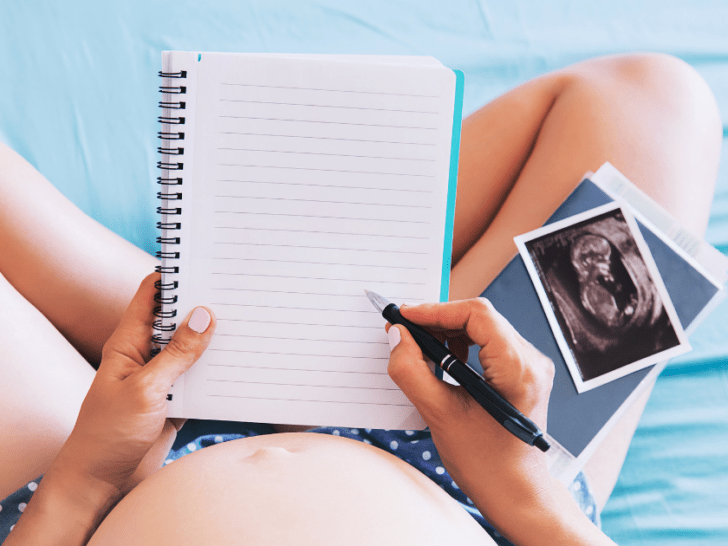 pregnant woman with ultrasound photos and blank notebook ready for pregnancy journal prompts
